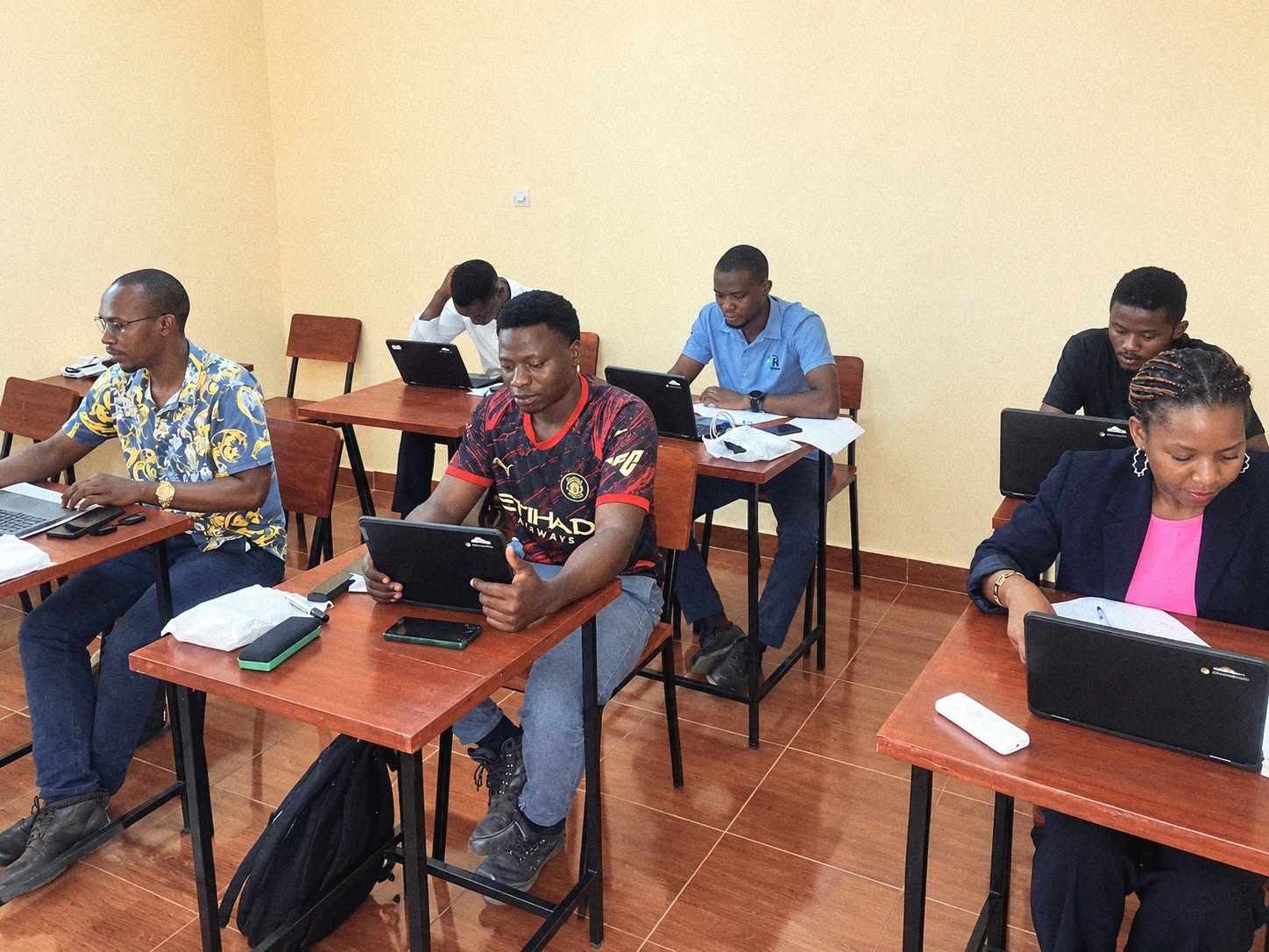 Seis alunos a utilizar computadores e tablets na sala de aula da Starbridge em Tete